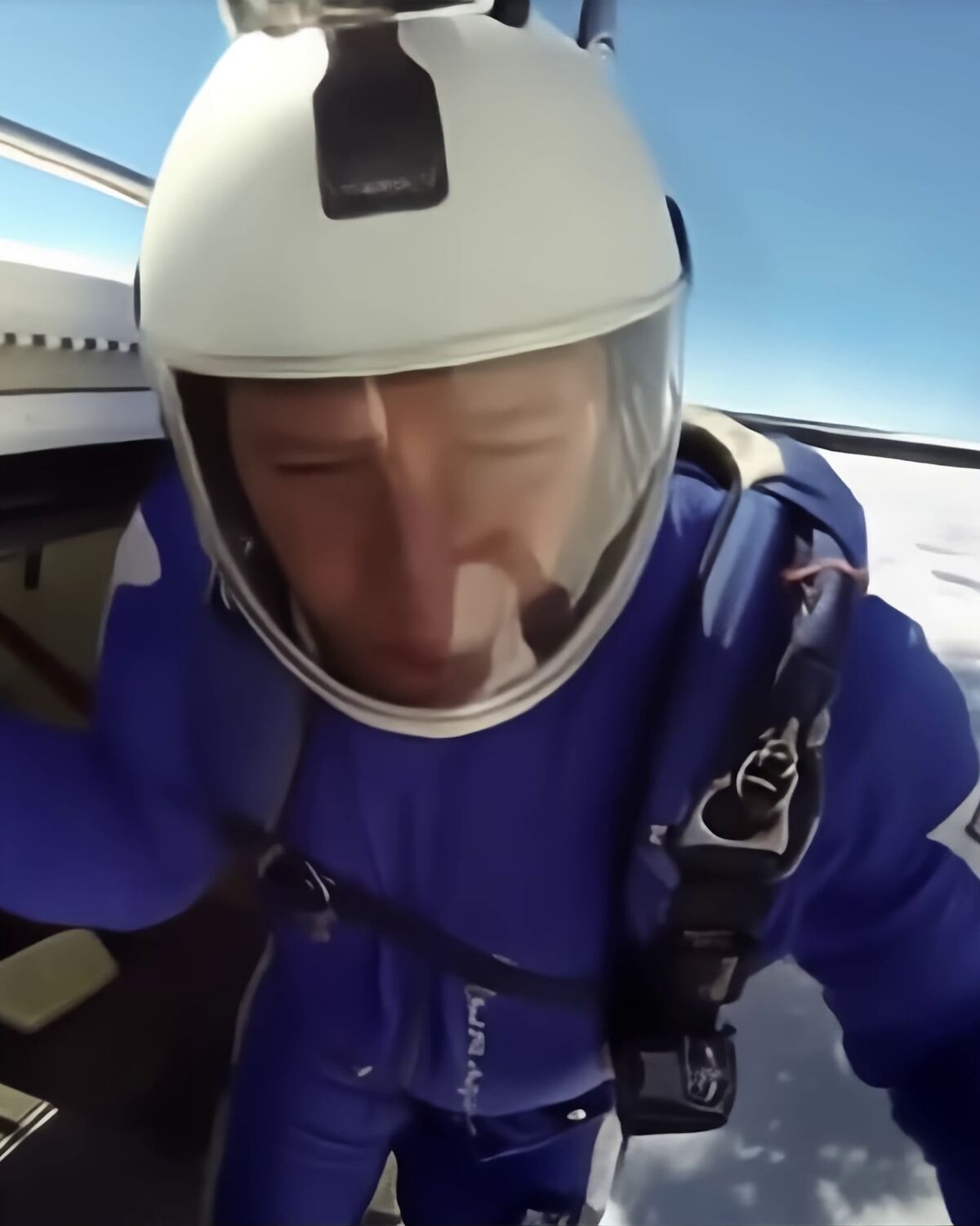 Brian Germain in a helmet, crouched in the open door of an aircraft, eyes down