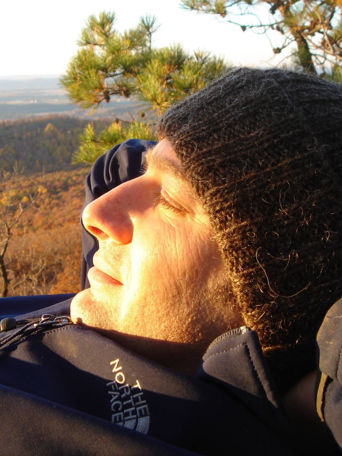 Brian Germain resting on a hillside in low golden sun, eyes closed